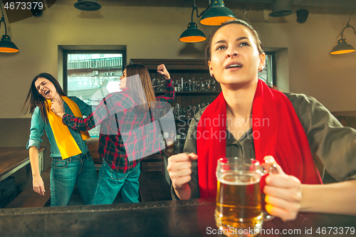 Image of Sport, people, leisure, friendship and entertainment concept - happy football fans or female friends drinking beer and celebrating victory at bar or pub