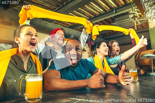 Image of Sport, people, leisure, friendship and entertainment concept - happy football fans or male friends drinking beer and celebrating victory at bar or pub