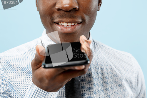 Image of Indoor portrait of attractive young black man holding blank smartphone