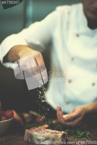 Image of Chef putting salt on juicy slice of raw steak