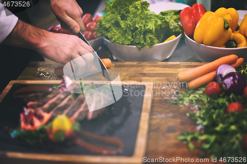 Image of closeup of Chef hands serving beef steak