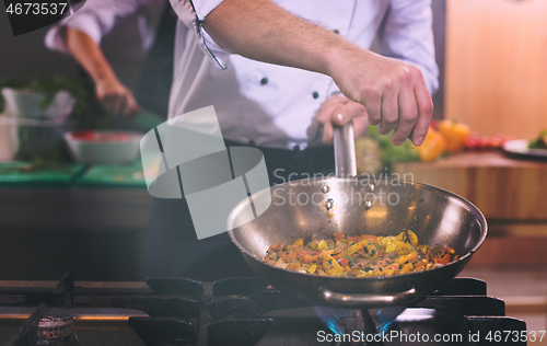 Image of chef putting spices on vegetables in wok