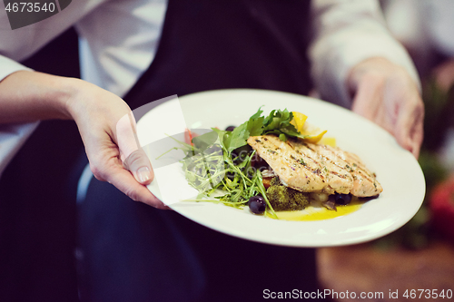 Image of Chef hands holding dish of fried Salmon fish fillet