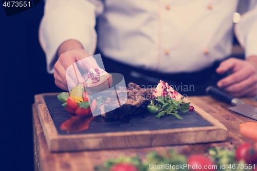 Image of closeup of Chef hands serving beef steak