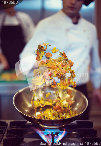 Image of chef flipping vegetables in wok