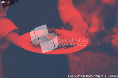 Image of Chef hands holding dish of fried Salmon fish fillet