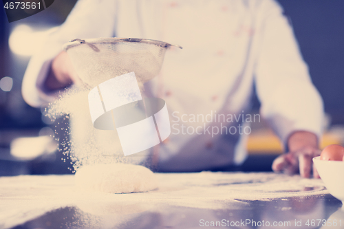 Image of chef sprinkling flour over fresh pizza dough