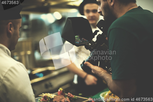 Image of videographer recording while team cooks and chefs preparing meal