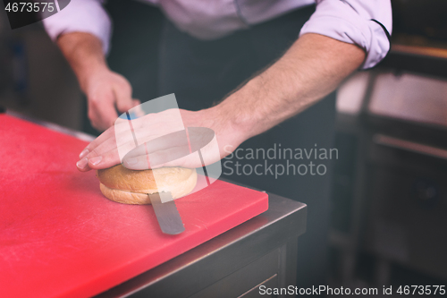 Image of chef hands cutting rolls for burger