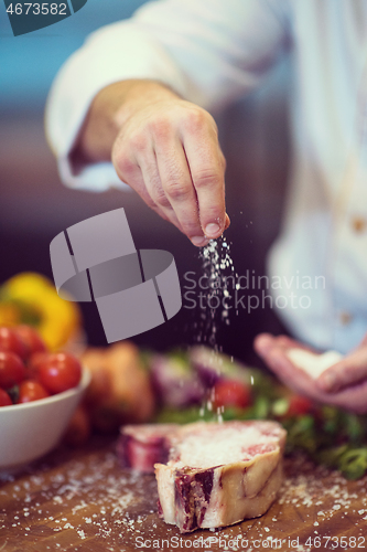 Image of Chef putting salt on juicy slice of raw steak