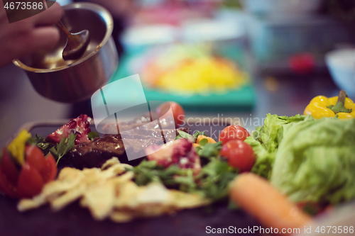 Image of Chef hand finishing steak meat plate