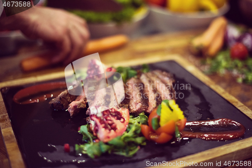 Image of closeup of Chef hands serving beef steak