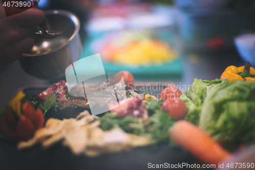 Image of Chef hand finishing steak meat plate