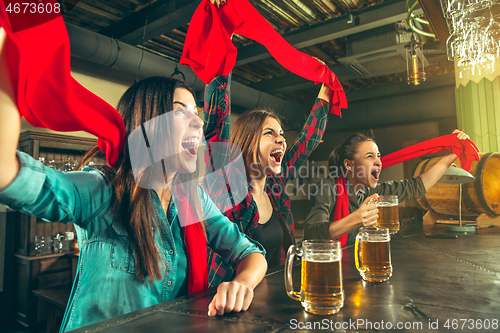 Image of Sport, people, leisure, friendship and entertainment concept - happy football fans or female friends drinking beer and celebrating victory at bar or pub