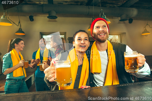 Image of Sport, people, leisure, friendship and entertainment concept - happy football fans or male friends drinking beer and celebrating victory at bar or pub