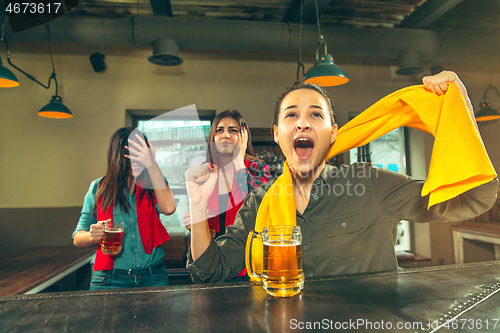 Image of Sport, people, leisure, friendship and entertainment concept - happy football fans or female friends drinking beer and celebrating victory at bar or pub