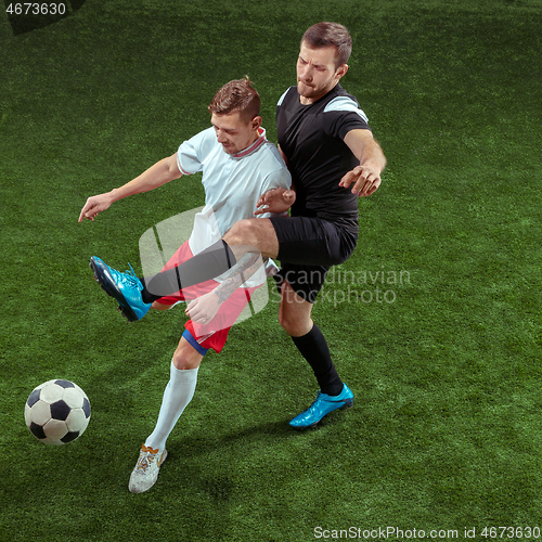 Image of Football players tackling ball over green grass background