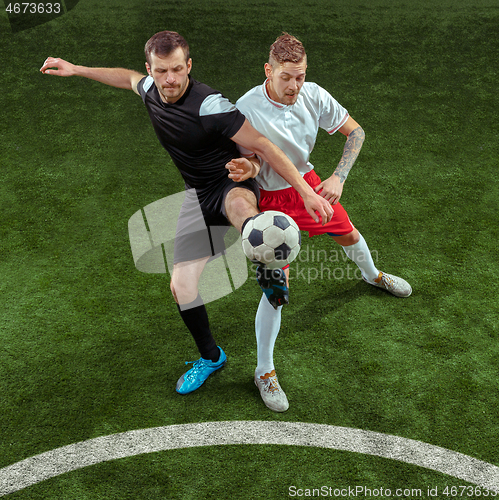 Image of Football players tackling ball over green grass background