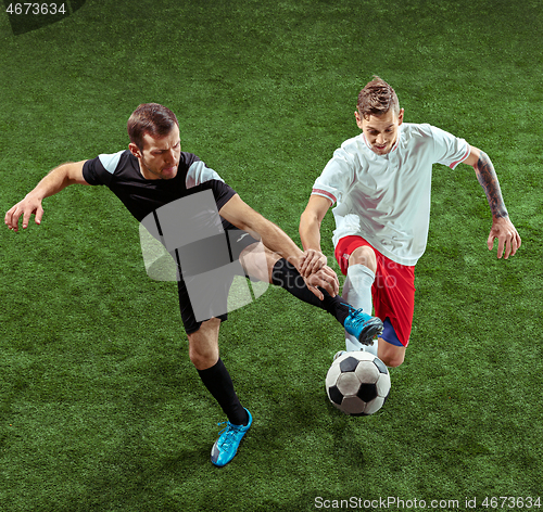 Image of Football players tackling ball over green grass background