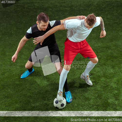 Image of Football players tackling ball over green grass background