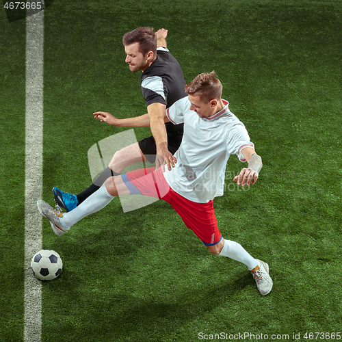 Image of Football players tackling ball over green grass background