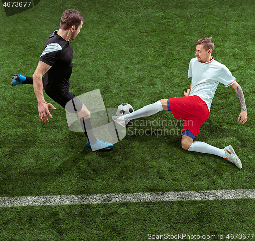 Image of Football players tackling ball over green grass background
