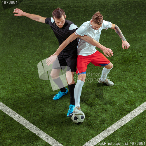 Image of Football players tackling ball over green grass background