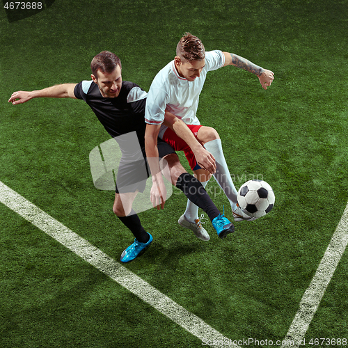 Image of Football players tackling ball over green grass background