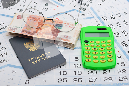 Image of Business still life from a bundle of five thousandth bills, a calculator, glasses and a work book