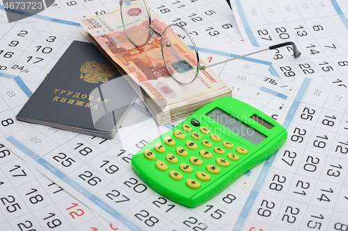 Image of Labor book, a bundle of money, glasses and a calculator lies on the background from the calendar