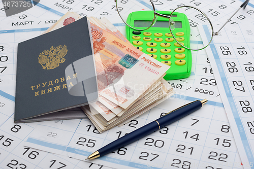 Image of A bundle of five-thousandth bills sticks out of the work book, next to it lies a calculator and glasses and a pen