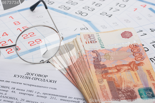 Image of Sale and purchase agreement of an apartment, a wad of money, a calendar and glasses