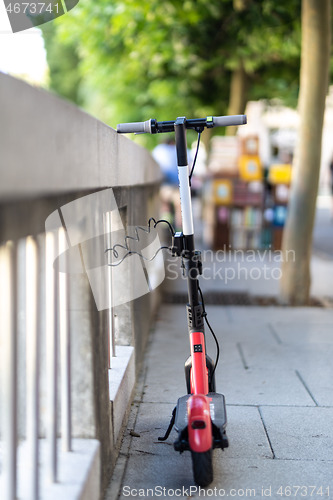 Image of Red electric scooter parked and safely chained to a fence. Eco friendly green modern urban mobility concept of sharing transportation with electric scooters for rent in Ljubljana, Slovenia