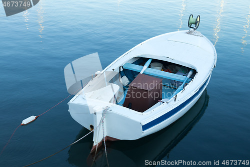 Image of Vintage old white wooden row boat on blue sea water