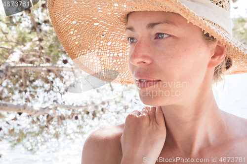 Image of Close up portrait of no makeup natural beautiful sensual woman wearing straw sun hat on the beach in shade of a pine tree