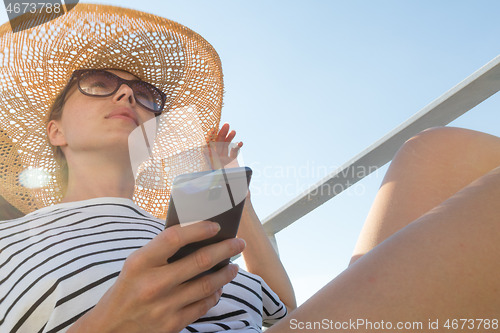 Image of Beautiful, romantic blonde woman on summer vacations traveling by cruse ship ferry boat holding and using mobile phone. Summer vacation lifestyle