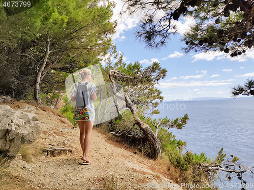 Image of Young active feamle tourist wearing small backpack walking on co