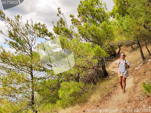 Image of Young active feamle tourist wearing small backpack walking on co