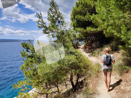 Image of Young active feamle tourist wearing small backpack walking on co