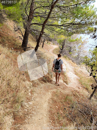 Image of Young active feamle tourist wearing small backpack walking on co