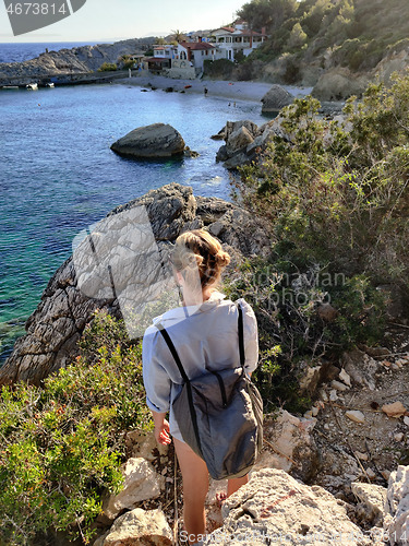 Image of Young active feamle tourist wearing small backpack walking on coastal path among pine trees enjoing beautiful costal view of Velo Zarace beach on Hvar island, Croatia. Travel and adventure concept