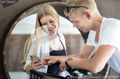 Image of Happy young couple using smart phone app outdoors in urban environment