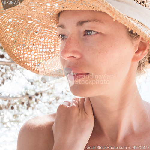 Image of Close up portrait of no makeup natural beautiful sensual woman wearing straw sun hat on the beach in shade of a pine tree