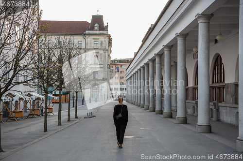 Image of Rear view of unrecognizable woman walking in empty old medieval Ljubljana city center during corona virus pandemic. Almost no people outside on streets