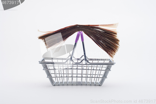 Image of A large stack of paper bills is on the handles of a grocery basket, front view