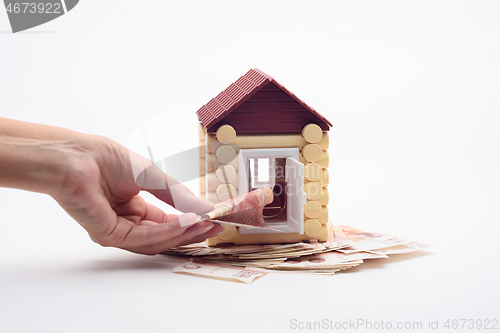 Image of Hand puts a bill into the door of the toy house