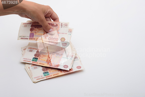 Image of Hand throws 5000 rubles banknotes on a white background