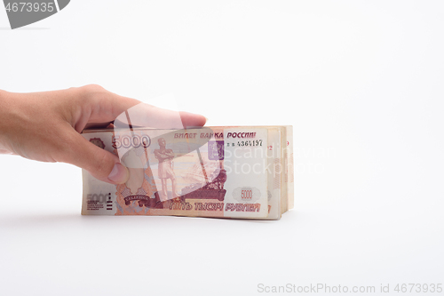 Image of Hand holds a bundle of banknotes, five thousandth bills on a white background