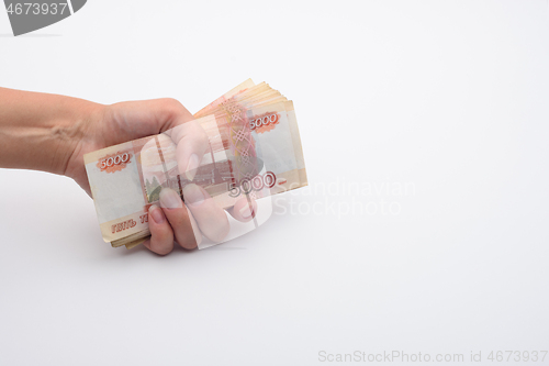 Image of Hand holds a stack of five thousandth bills in a fist