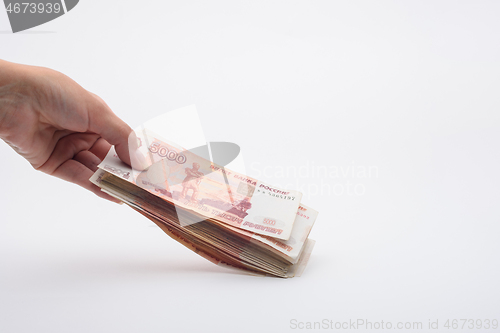 Image of Hand holds out a bundle of five thousandth Russian banknotes